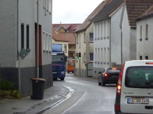 Mülltonnen, Asphalt und vor allem Autos prägen die Mitte unseres Dorfes. Von Aufenthaltsqualität ist hier keine Rede. Was machen wir bloß, wenn die Autos weg sind? Foto: Nissen